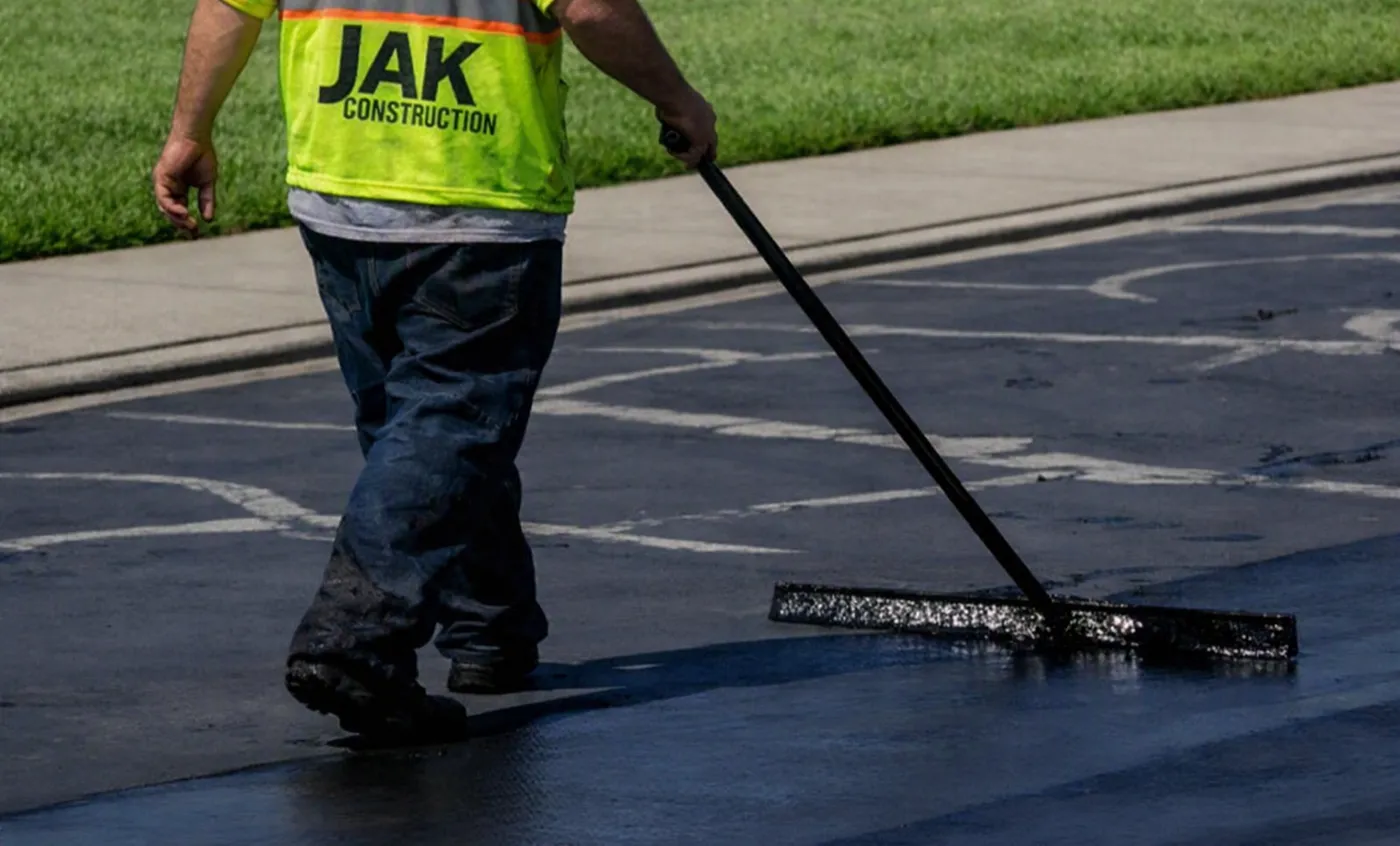 JAK crew squeegeeing sealcoat across a parking lot