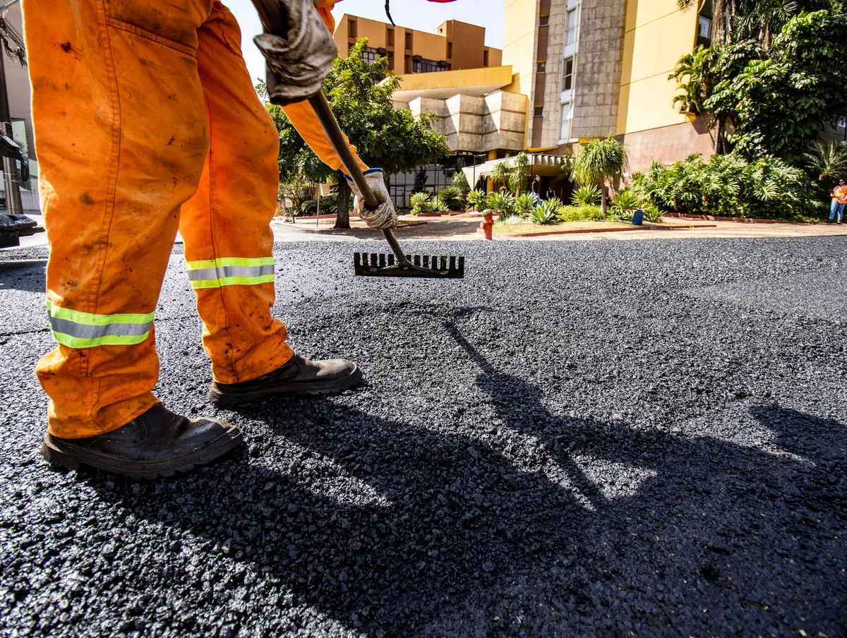 Worker raking hot asphalt